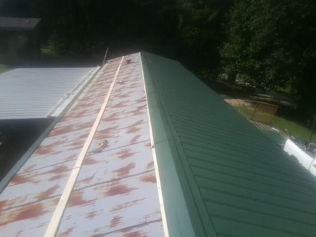 Old rusted panels beside newly installed green metal roofing — Wind Damage Roof Repair by Roofing Brothers in Bremen
